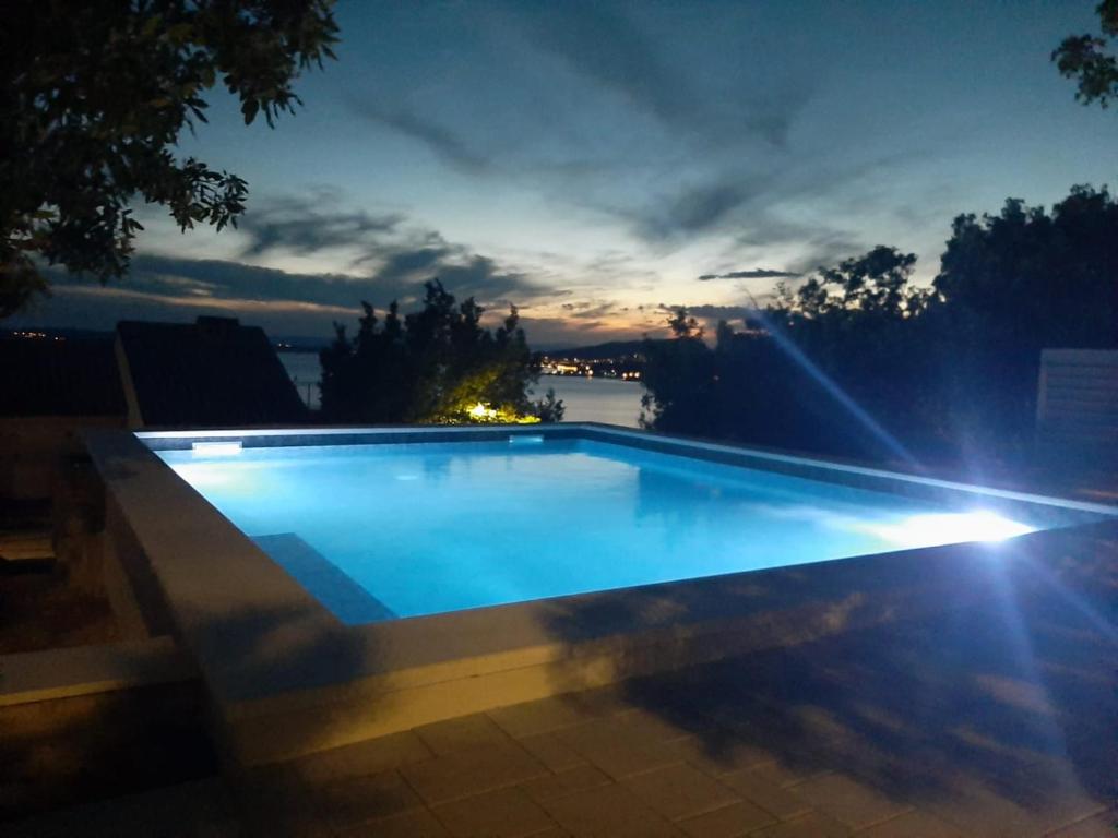 una piscina por la noche con las luces encendidas en Villa Barbara, en Klenovica