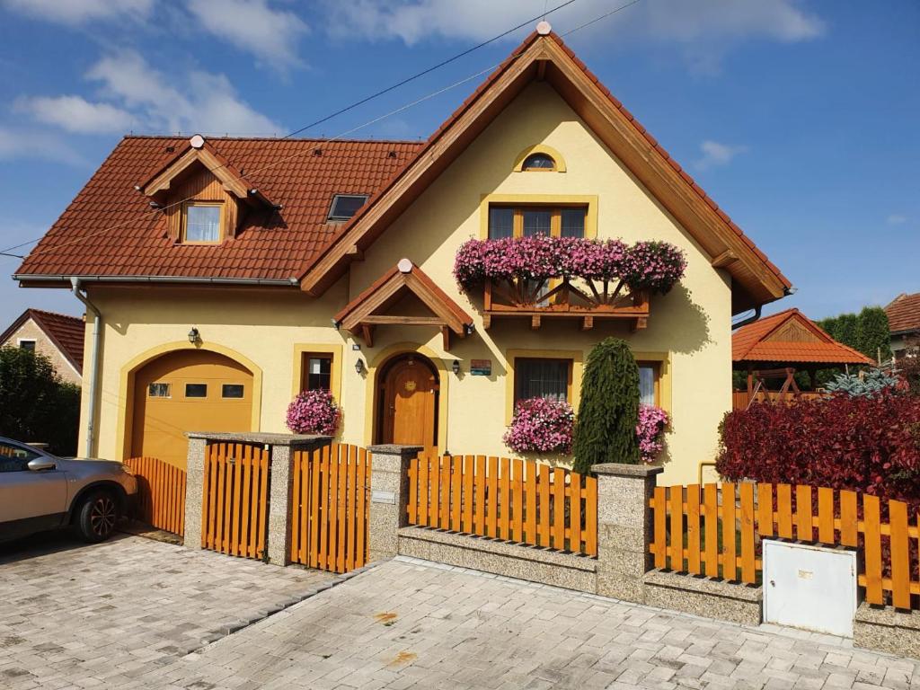 uma casa amarela com uma cerca e flores roxas em Žltý dom Vrbov em Vrbov