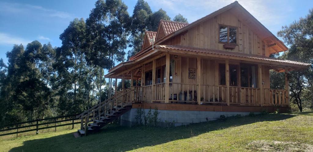 a large wooden house with a porch and stairs at Chalés Sol da Serra in Rio Rufino