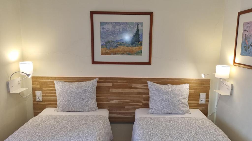 two beds in a room with two lights on the wall at Margarida Guest House - Rooms in Almada