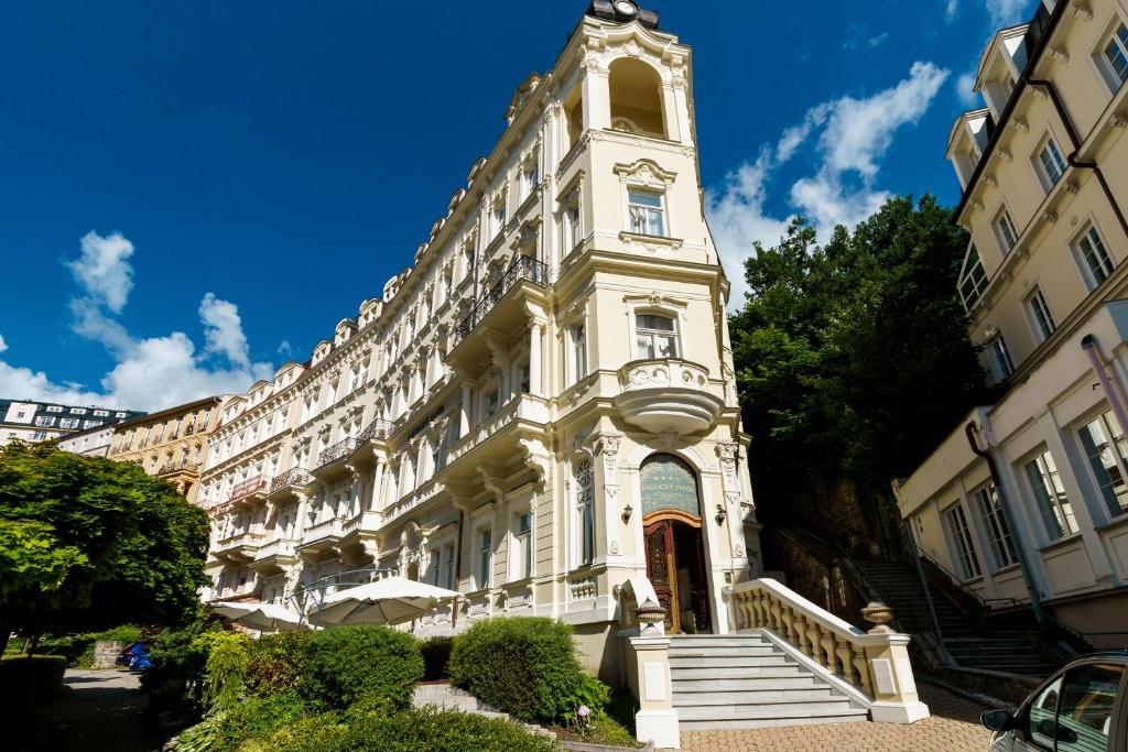 un grand bâtiment blanc avec une tour d'horloge dans l'établissement Spa Hotel Anglický Dvůr, à Karlovy Vary