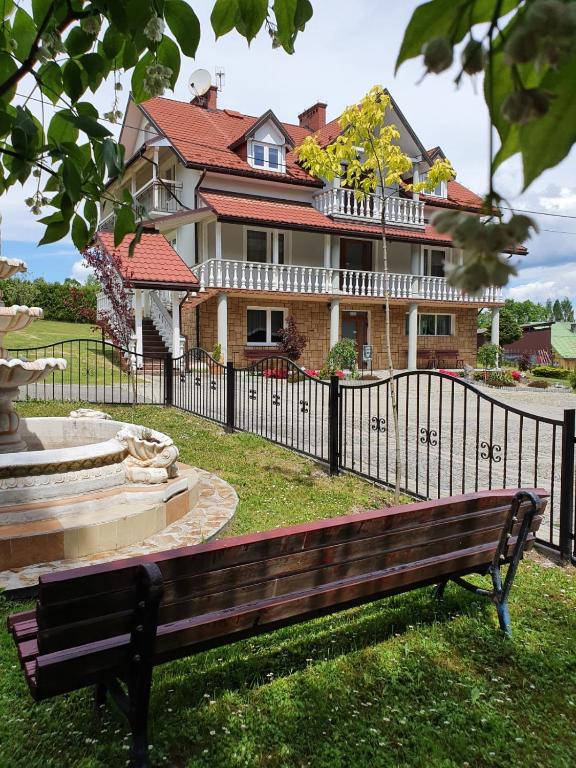 a bench in front of a house with a fence at Leśne Zacisze in Weremień