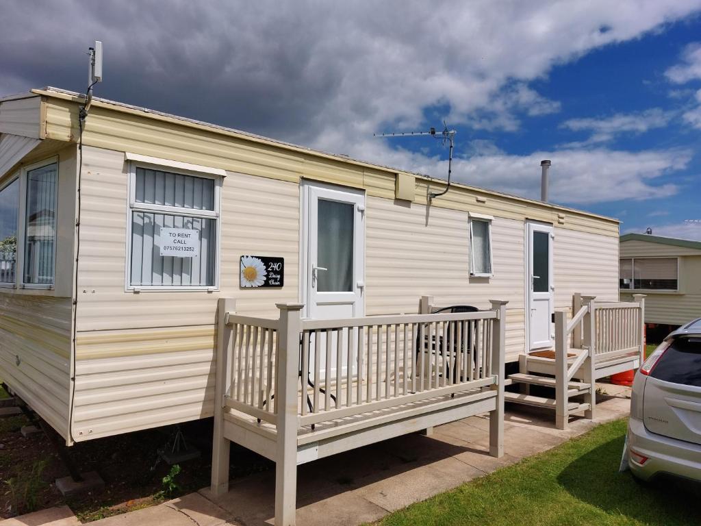 a white caravan with a porch and a car at 6 berth static caravan, sealands holiday park ingoldmells, skegness in Skegness