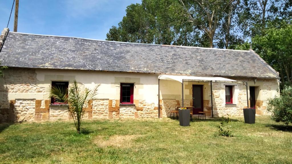 een oud stenen huis met rode ramen en een tuin bij Gîte de l'Octroy Poitou in Oiron