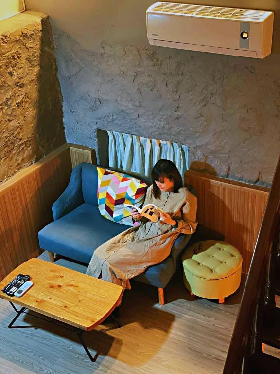 a woman sitting on a chair in a room at Taipei Jinguashi Cloud Mountain Homestay B&amp;B in Jiufen