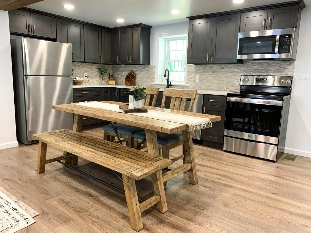 eine Küche mit einem Holztisch, Bänken und einem Kühlschrank in der Unterkunft Newly Remodeled Stouchsburg Cottage in Myerstown