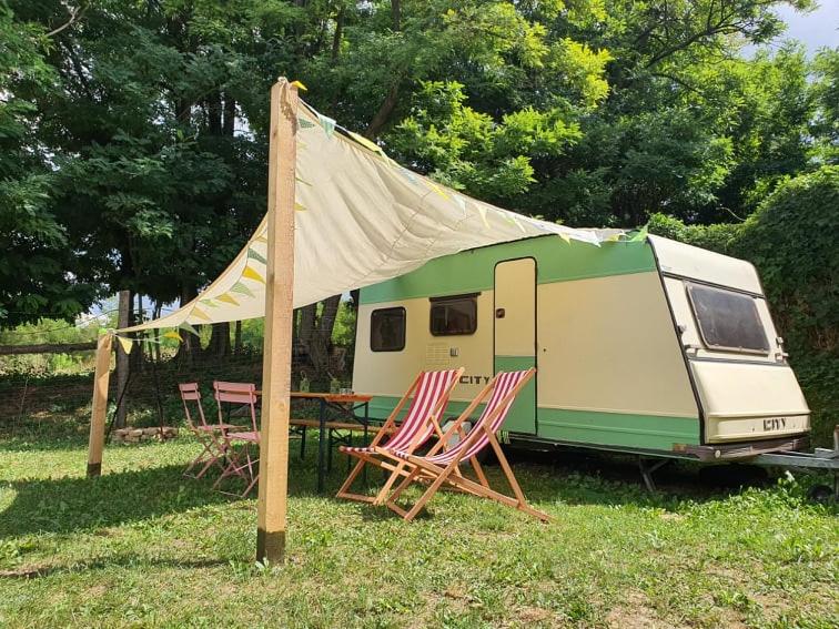 Koppány Pines Rewild Escapes - Vintage Caravan في Koppányszántó: خيمة وكراسي وطاولة أمام مقطورة