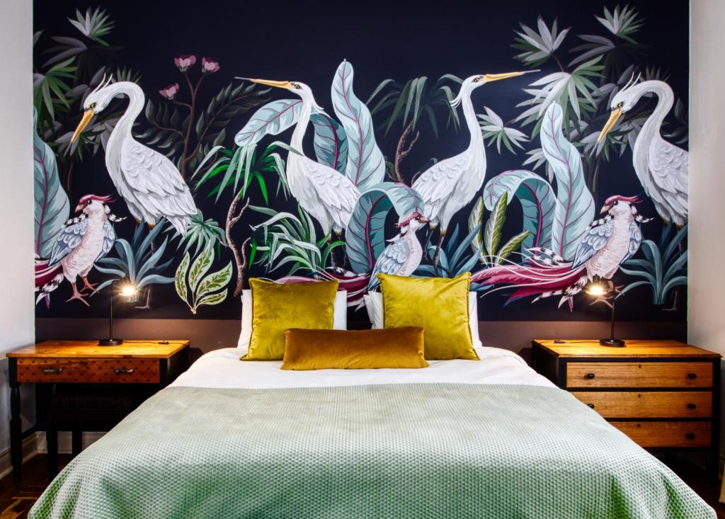 a bedroom with a large bed with a tropical wallpaper at The BeeKeeper's Inn in Louis Trichardt