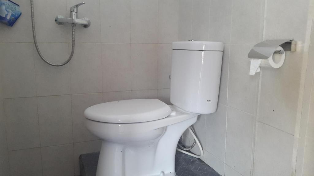 a white toilet in a bathroom with a shower at Meme Royak Homestay in Munduk