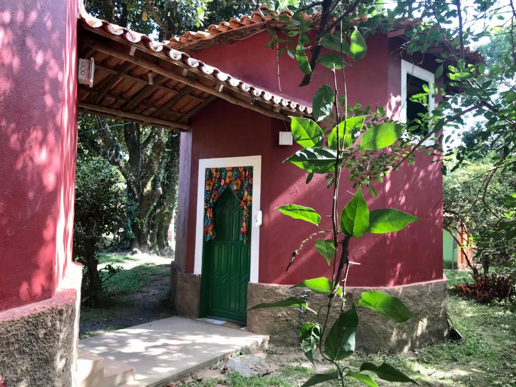 a red house with a green door and a tree at Chalé Raio De Sol in Vale do Capao