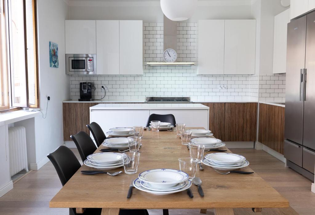 un tavolo in legno con piatti e bicchieri in una cucina di 2ndhomes Luxurious 144 m2 Stylish 3 Bedroom Center Apartment a Helsinki