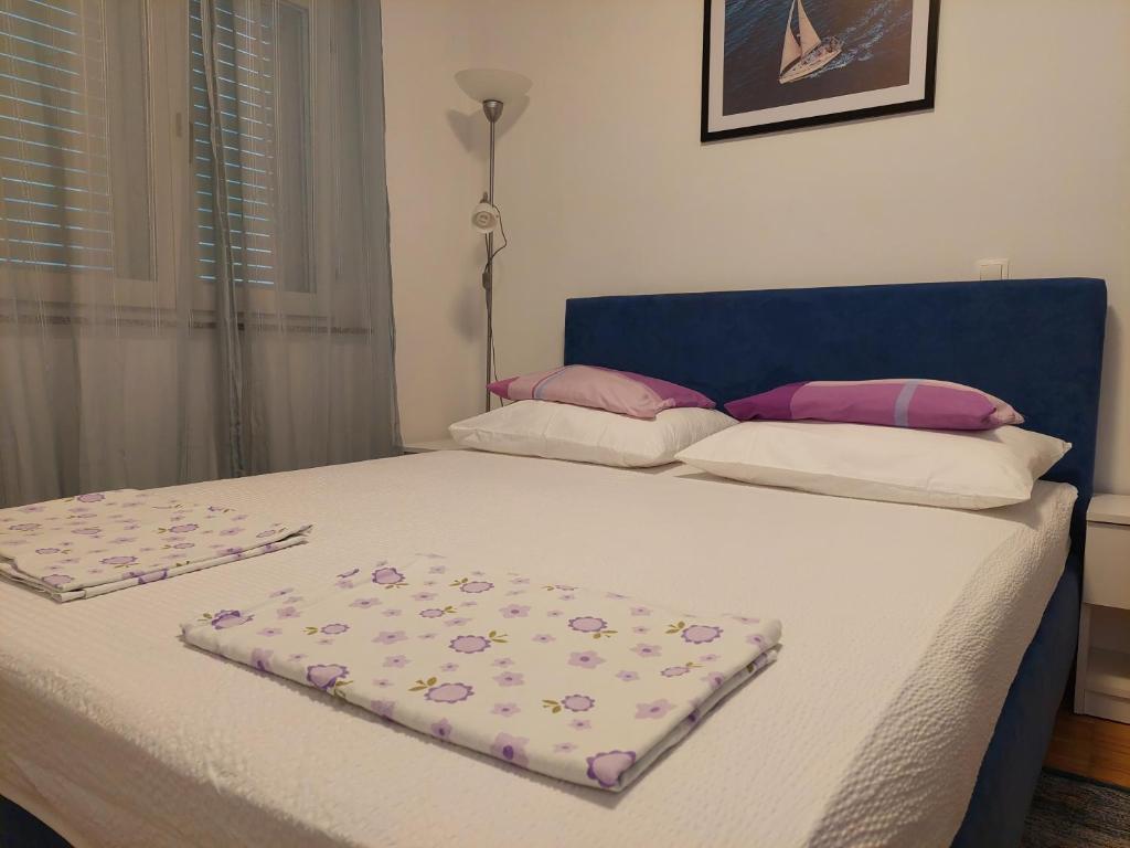 a bed with a blue head board with flowers on it at Apartman Zrina Oštro in Kraljevica