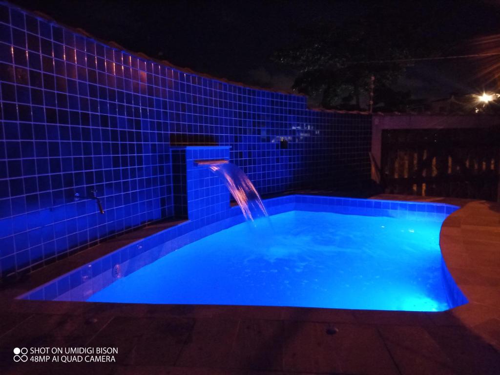 una piscina por la noche con una cascada en Casa com piscina , churrasqueira, Wi-Fi, em rua de Areia à 1km da praia, bairro sussegado, proíbido uso de som extremamente alto ideal para descansar, en Itanhaém