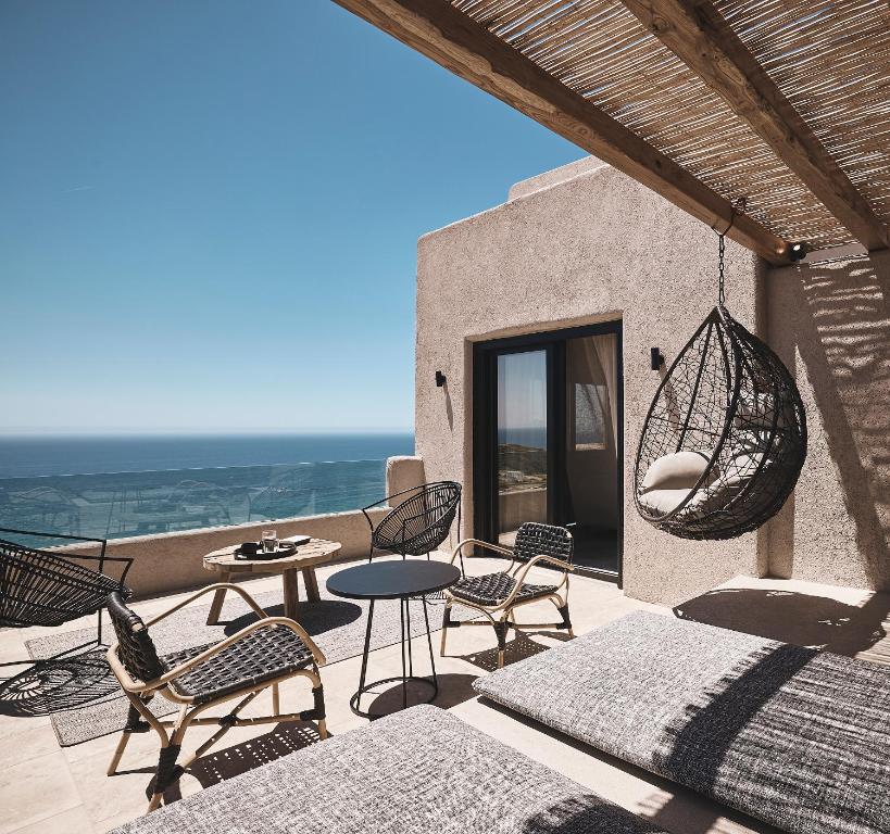 a patio with chairs and a table and a swing at Noma Milos - Delmar Collection in Provatas