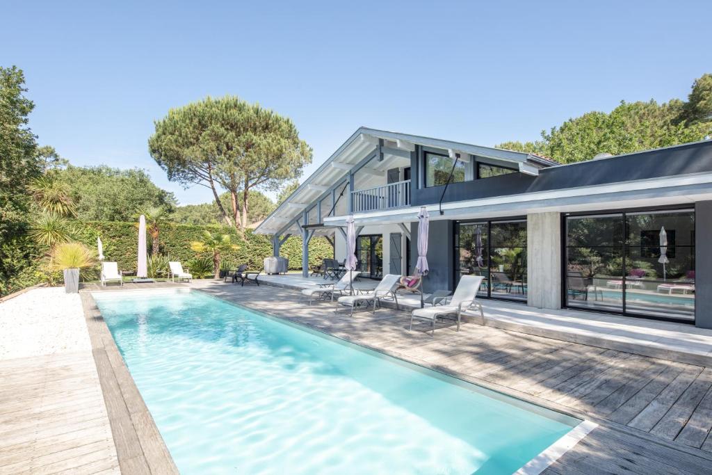 a swimming pool in front of a house at Ref 111 Seignosse, Villa de standing 4 étoiles partiellement climatisée avec piscine chauffée et Wifi au calme sur terrain 1100m2 in Seignosse