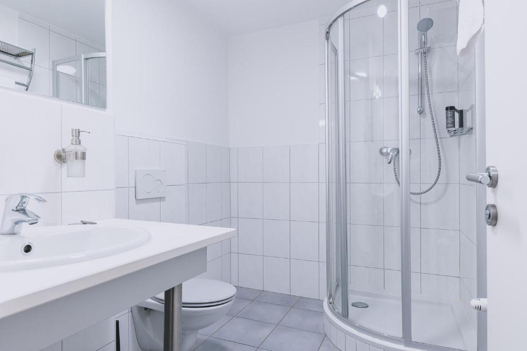 biała łazienka z prysznicem i umywalką w obiekcie Alpine City Living by we rent, SUMMERCARD INCLUDED w mieście Zell am See