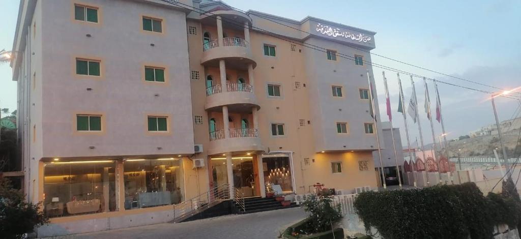 un gran edificio con banderas delante en بيت السلطانة للشقق الفندقية شمال محافظة النماص, en Ash Shaykh