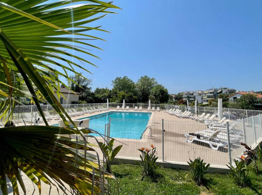 a swimming pool with chairs and a fence around it at Appartement 11 en duplex - LES SUITES DE ROBINSON - Résidence avec piscine en bord de Siagne, à Mandelieu-La-Napoule in Mandelieu-la-Napoule