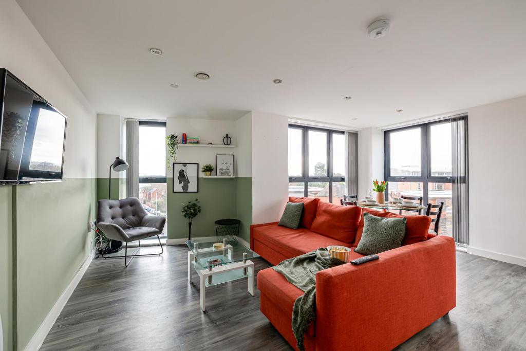 una sala de estar con 2 sofás naranjas y una mesa. en Stunning 2 bed apt with free parking close to CC en Mánchester