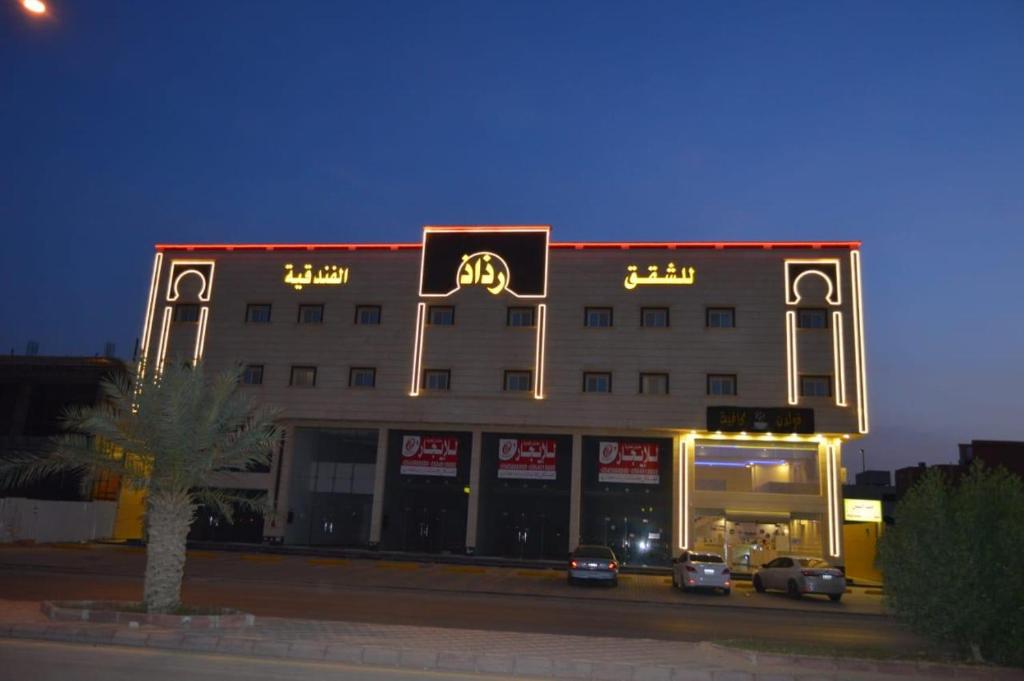 un bâtiment avec des panneaux de néon à l'avant dans l'établissement فندق رذاذ, à Al Kharj