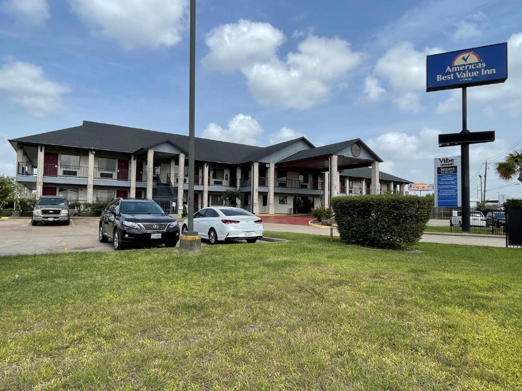 een gebouw met twee auto's geparkeerd op een parkeerplaats bij Americas Best Value Inn Hobby Airport in Houston