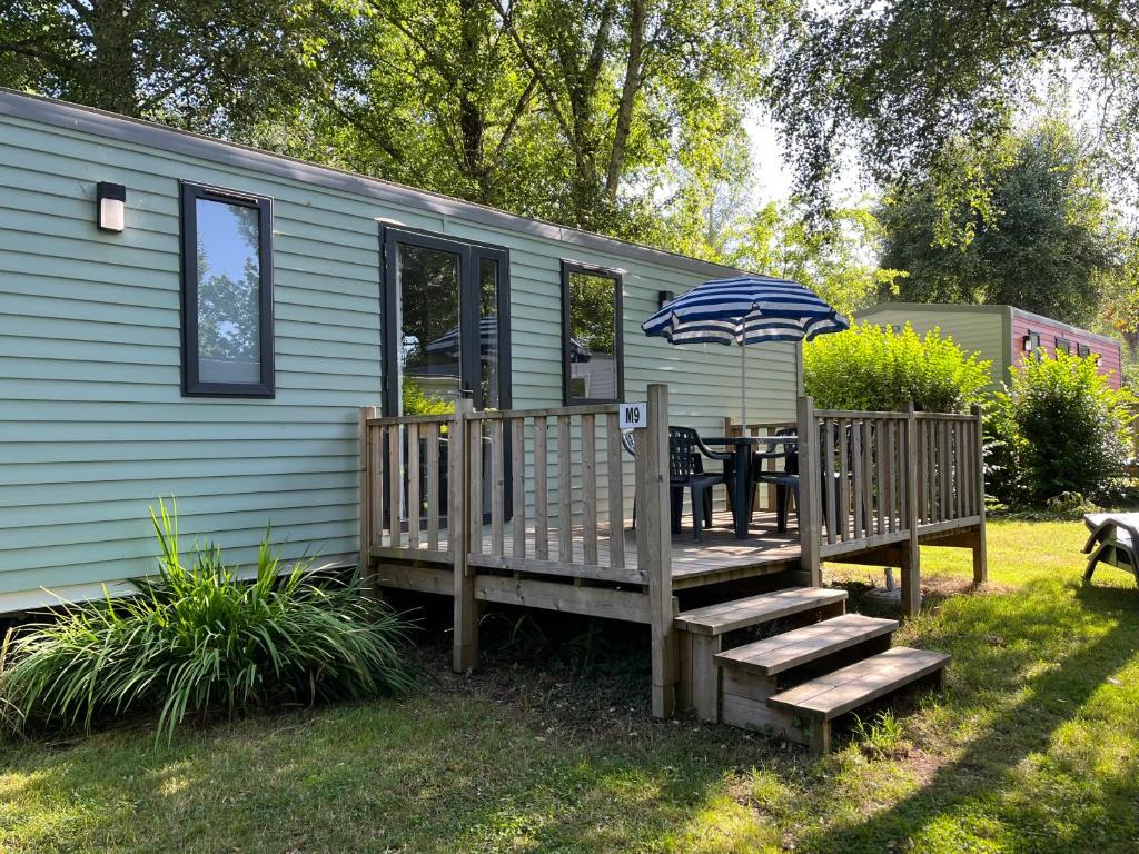 um deque com uma mesa e um guarda-chuva em Mobilhome tout confort M9 domaine de Lanniron em Quimper