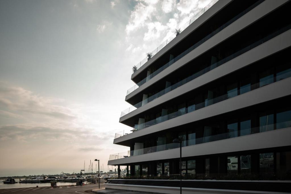 a tall building with the ocean in the background at Laguna Faro Suites - Adults Only & Free Beach in Grado