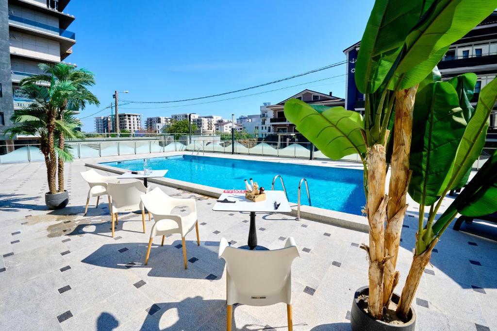 un patio con tavoli e sedie accanto alla piscina di Infinity Luxury Studio - NorD10 by Alezzi a Mamaia Nord - Năvodari