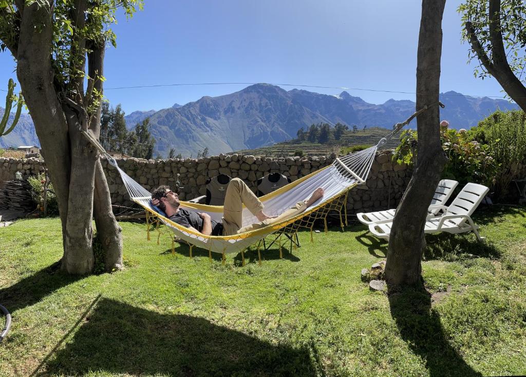 een man in een hangmat in een tuin bij La Casa de Santiago Hotel in Cabanaconde