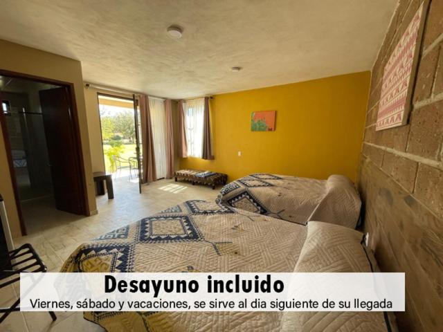 1 dormitorio con cama y pared amarilla en Posada Campestre Tasquillo, en Tasquillo