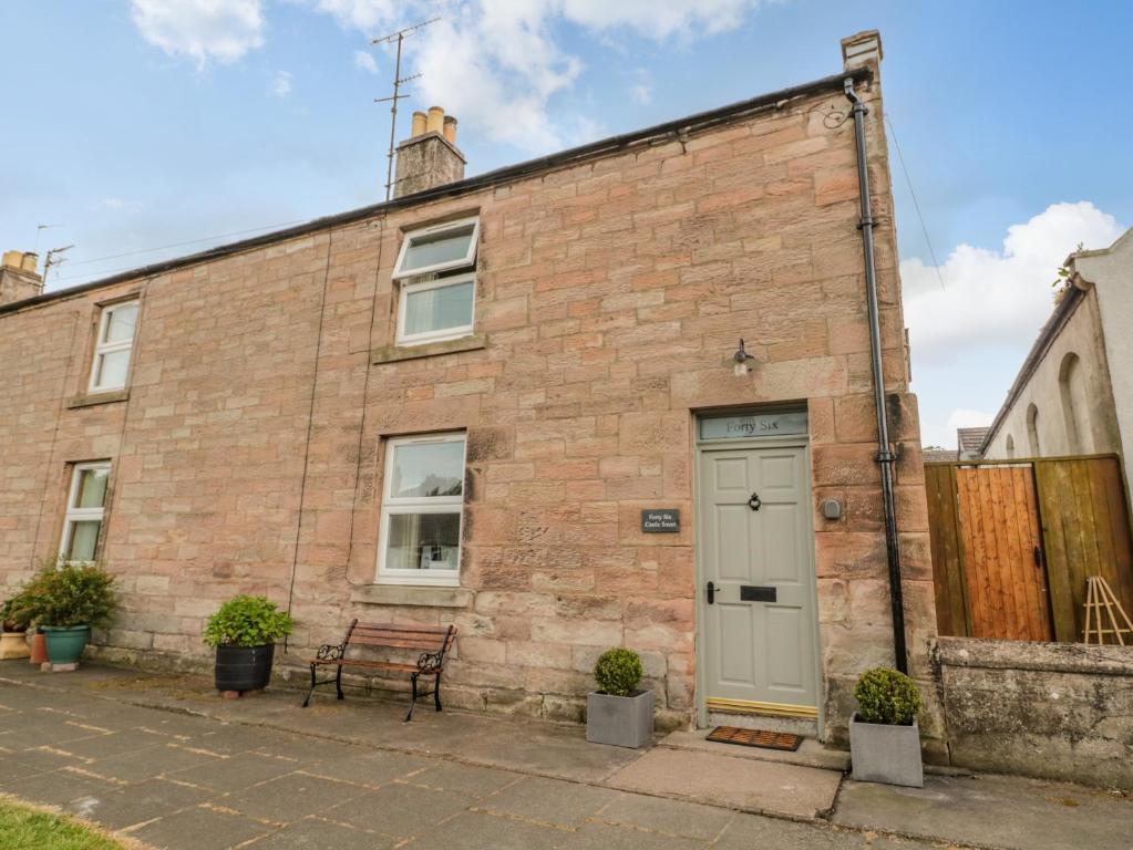 an old brick building with a door and a bench at 46 Castle Street in Berwick-Upon-Tweed