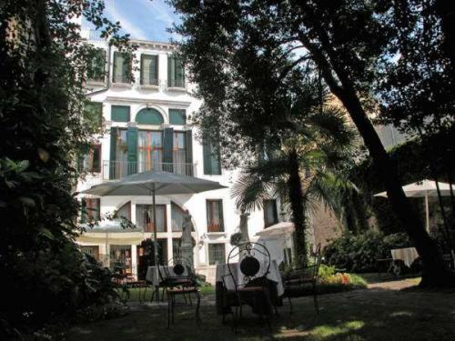 una gran casa blanca con un paraguas delante en Hotel Palazzo Abadessa, en Venecia