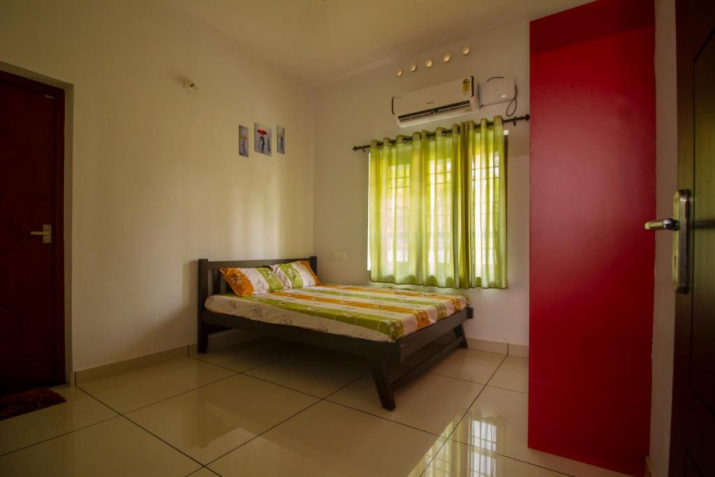 a couch in a room with a window and a red door at Bachan's Casa in Cherai Beach