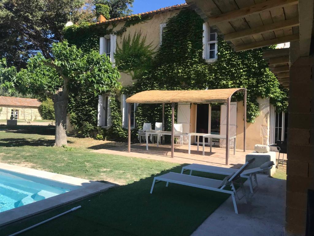 ein Haus mit einem Pool, einem Tisch und einem Sonnenschirm in der Unterkunft La Bastide Plein Sud de Marignan in Saint-Gilles