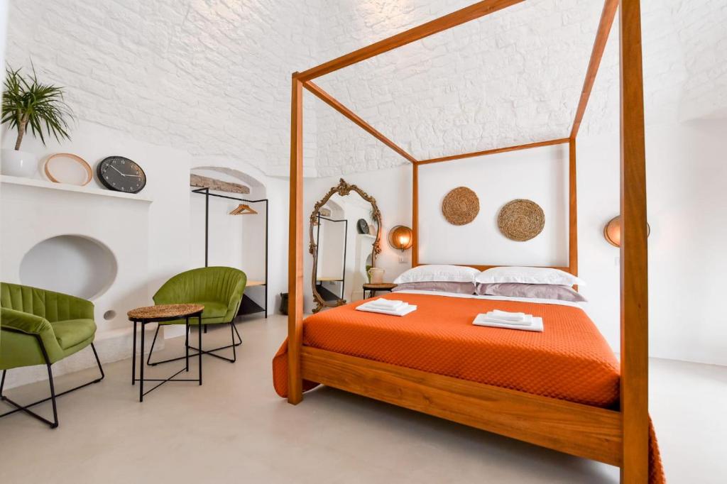 een slaapkamer met een hemelbed en 2 groene stoelen bij Corte Giotto Exclusive House in Carovigno