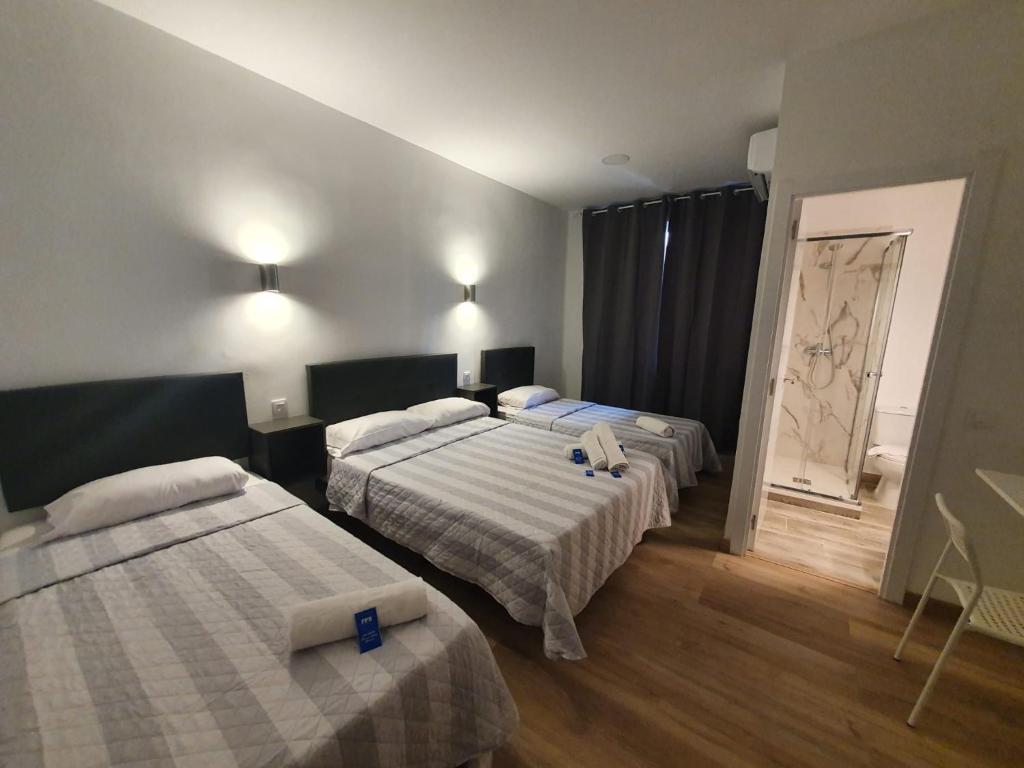 una camera d'albergo con due letti e uno specchio di Hostal Vara Madrid a Madrid