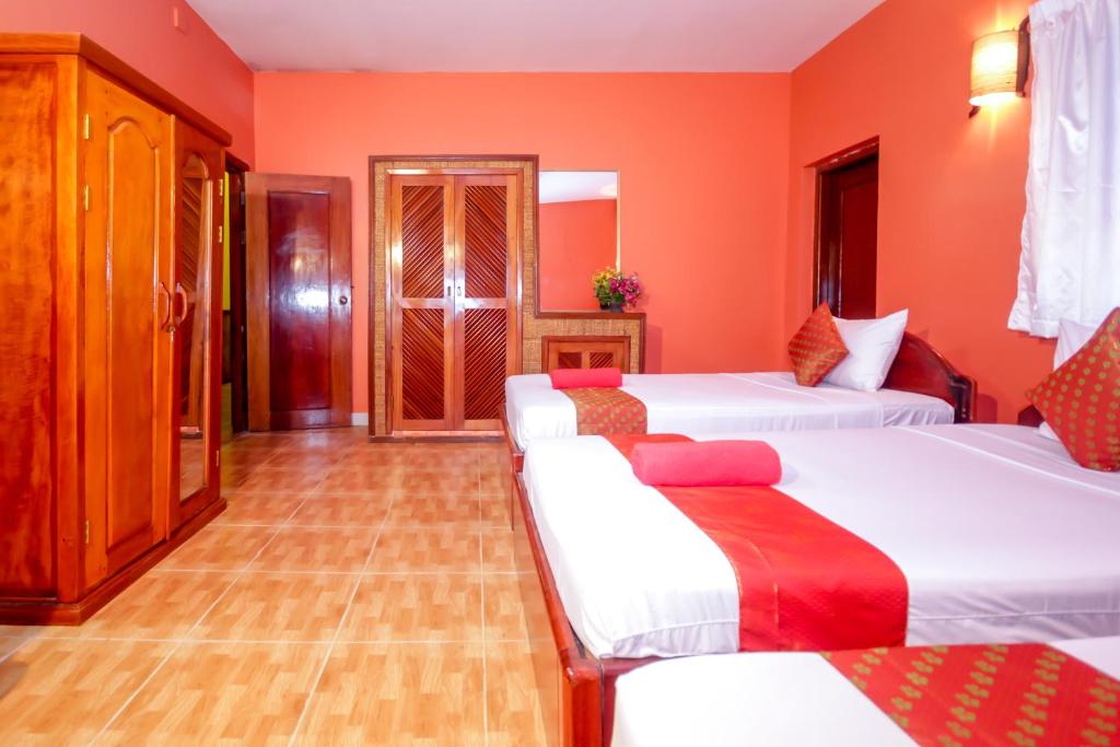 a bedroom with two beds and orange walls at Blossoming Romduol Boutique in Siem Reap