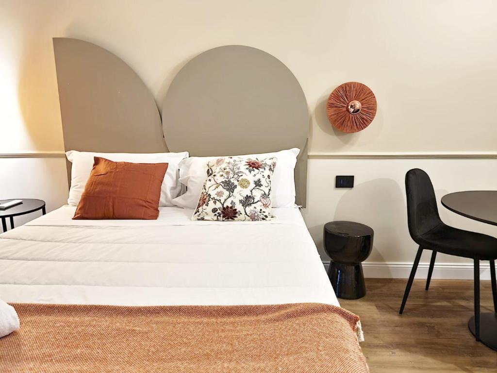 una camera da letto con un letto bianco con cuscini e un tavolo di TUTTOTONDO a Pescara