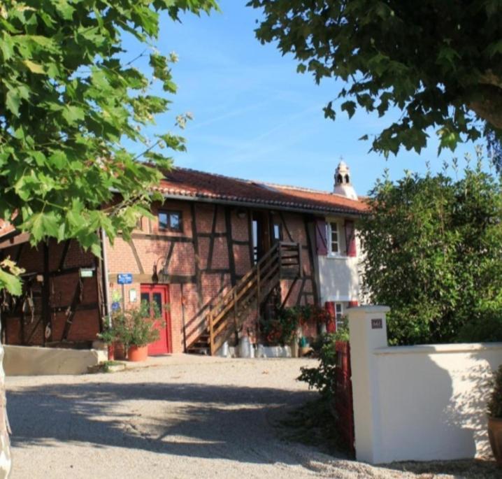 un gran edificio con una puerta roja y una escalera en Chambres d'hôtes Les Vignes, en Montcet