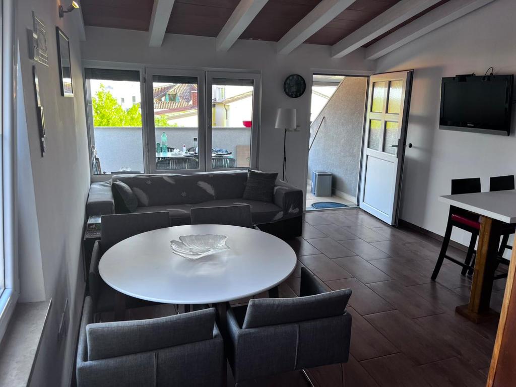 Una sala de estar con un sofá, una mesa y sillas. en Emonia apartman, en Novigrad Istria