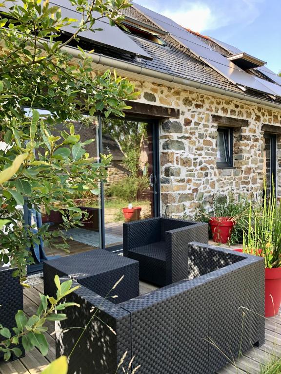 une terrasse avec des chaises noires et une maison en pierre dans l'établissement La vieille ferme, à Landévennec