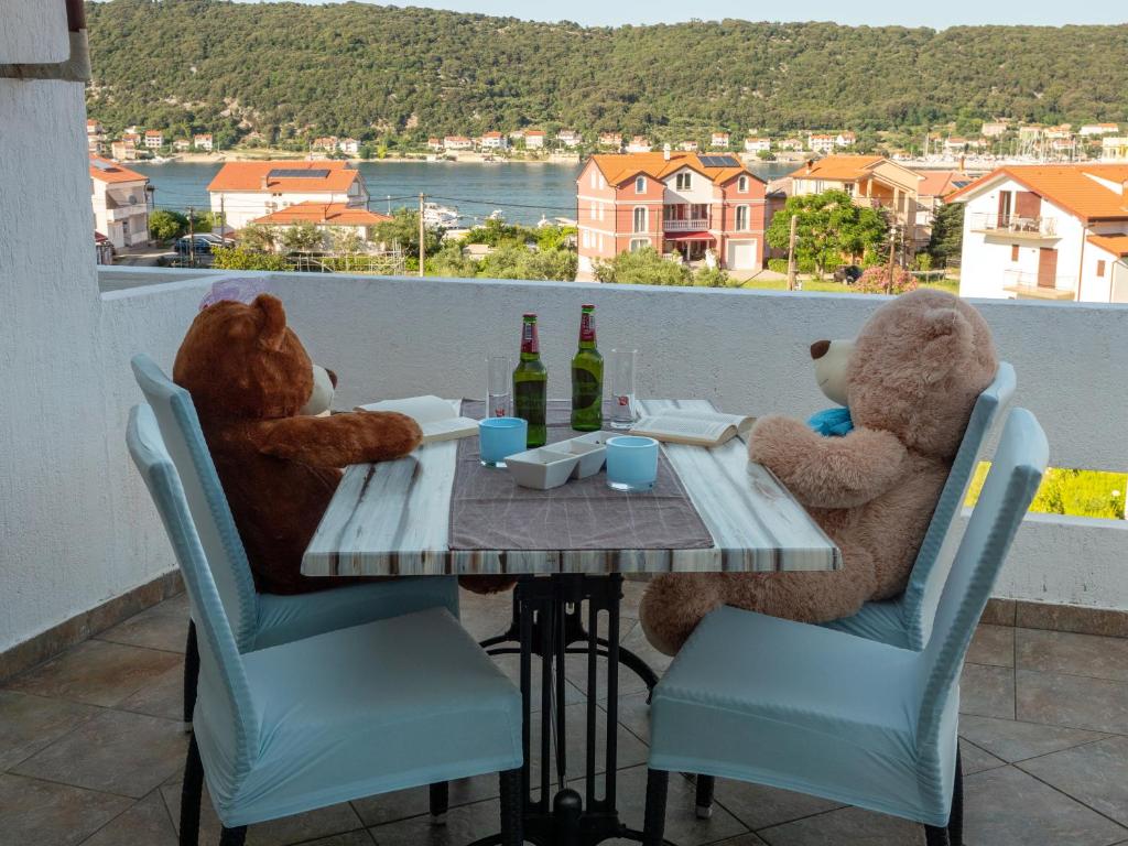 dos ositos de peluche sentados en una mesa en un balcón en Apartments Rezek en Supetarska Draga