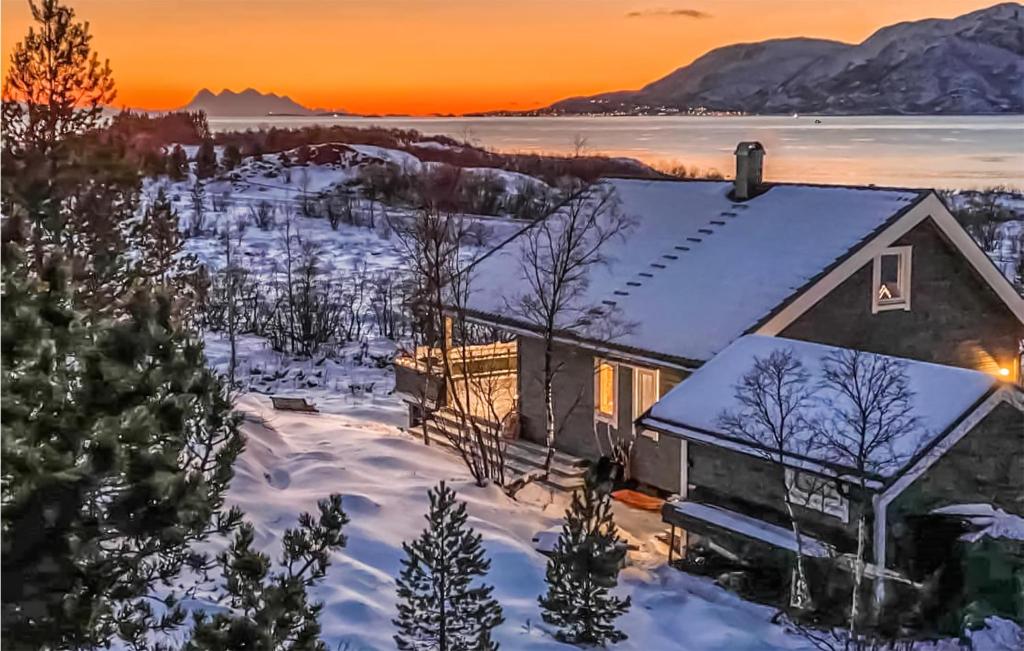 a house in the snow with the sunset in the background at Beautiful Home In Hol I Tjeldsund With Wifi 