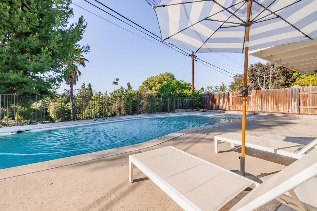 a swimming pool with an umbrella and two lounge chairs at @ Marbella Lane - Modern and Luxurious Design Home in Fullerton