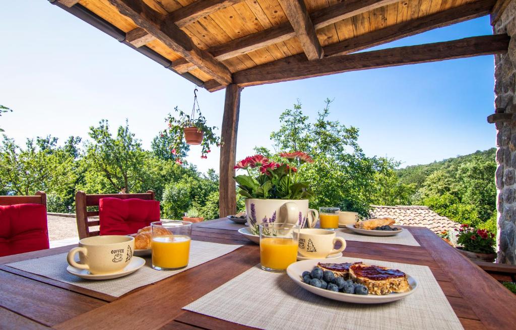 a wooden table with breakfast foods and orange juice at Guest house 'Villa Fani' Veprinac with jacuzzi in Veprinac