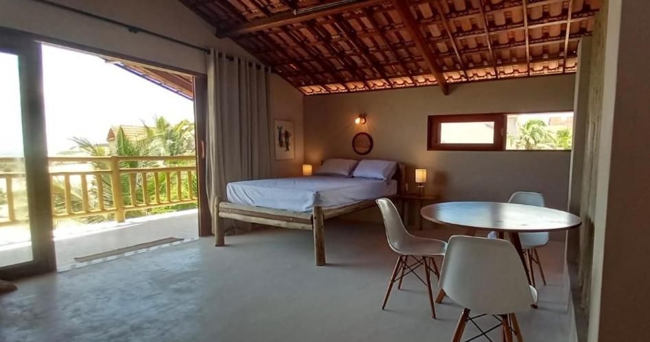 a bedroom with a bed and a table and chairs at Loft Canoa in Aracati