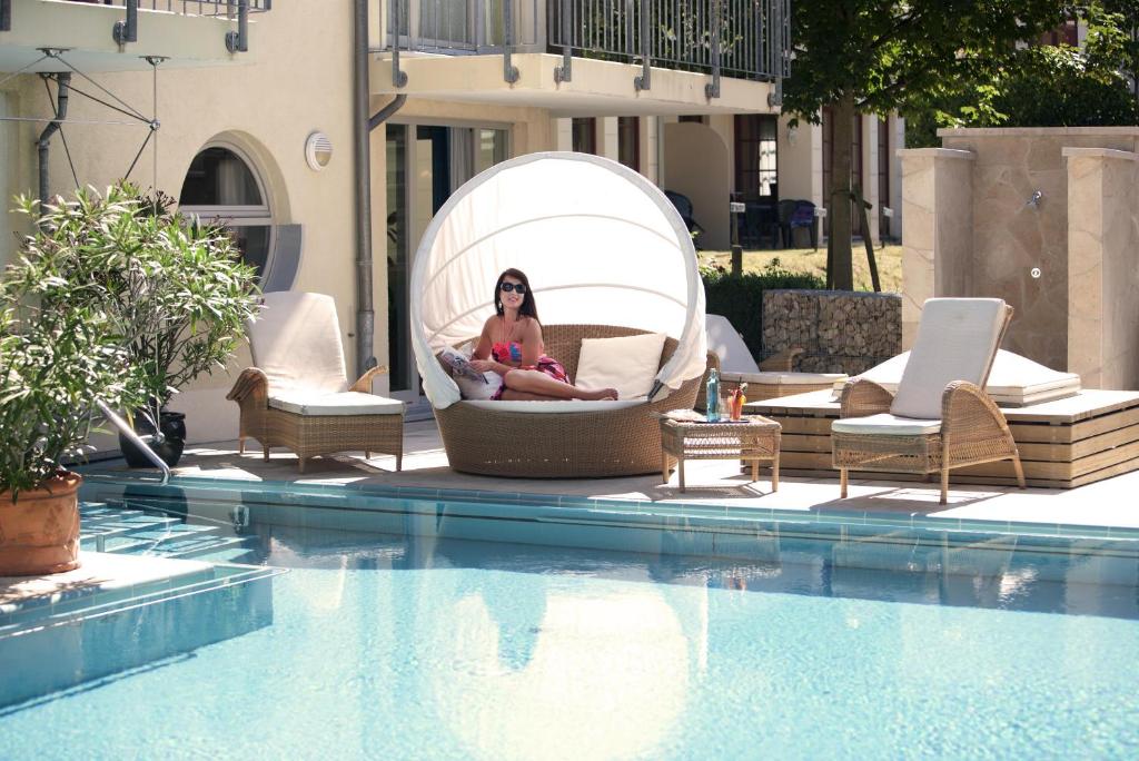 a woman sitting in a bubble chair next to a swimming pool at Strandhotel Heringsdorf in Heringsdorf