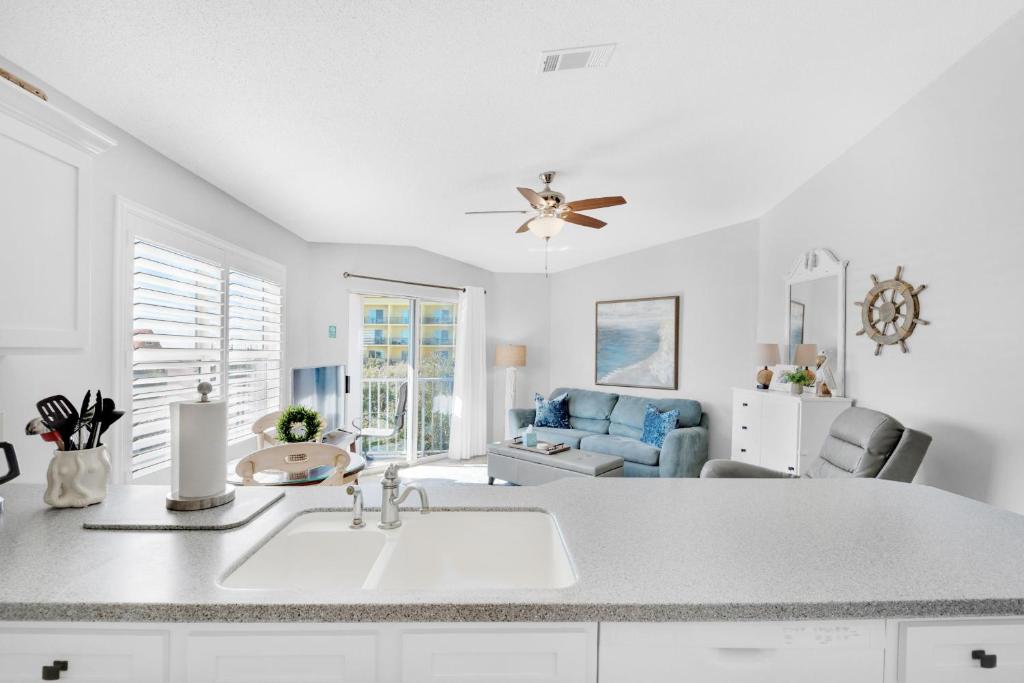 a white kitchen with a sink and a living room at Gulfview II 318 in Destin