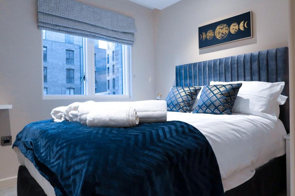 a bedroom with a large bed with a blue headboard at City Centre Luxury studio apartment suite with garden view in York