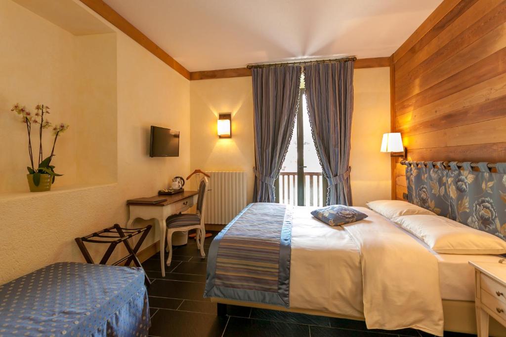 a hotel room with two beds and a desk at Hotel Lo Scoiattolo in Courmayeur